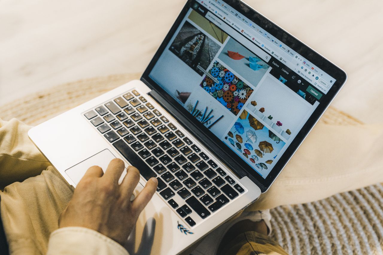 Une personne utilisant un ordinateur portable pour parcourir des sites de photos de stock. Travail en freelance dans un cadre chaleureux.